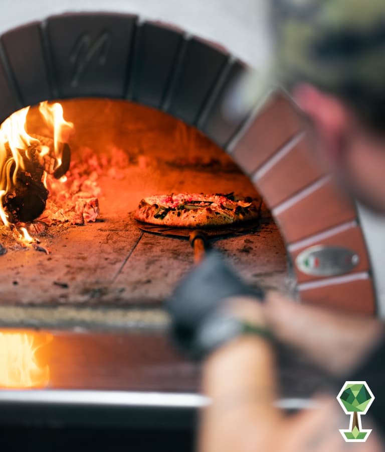 A pizza getting baked in a brick oven