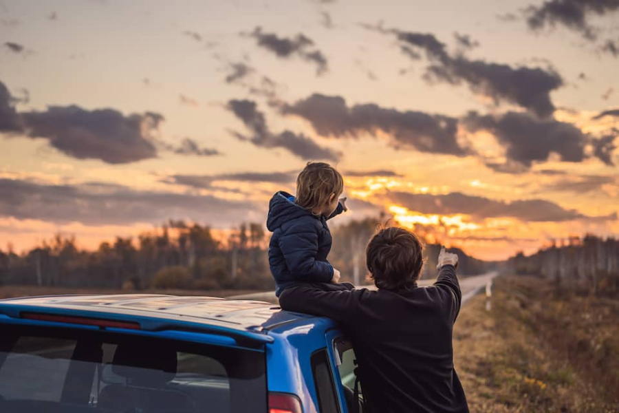 A child and their dad pointing towards the sunset