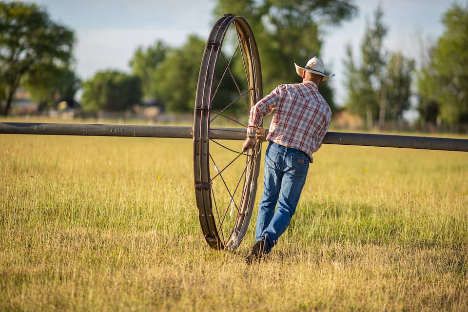 A person moving a large piece of farm equipment