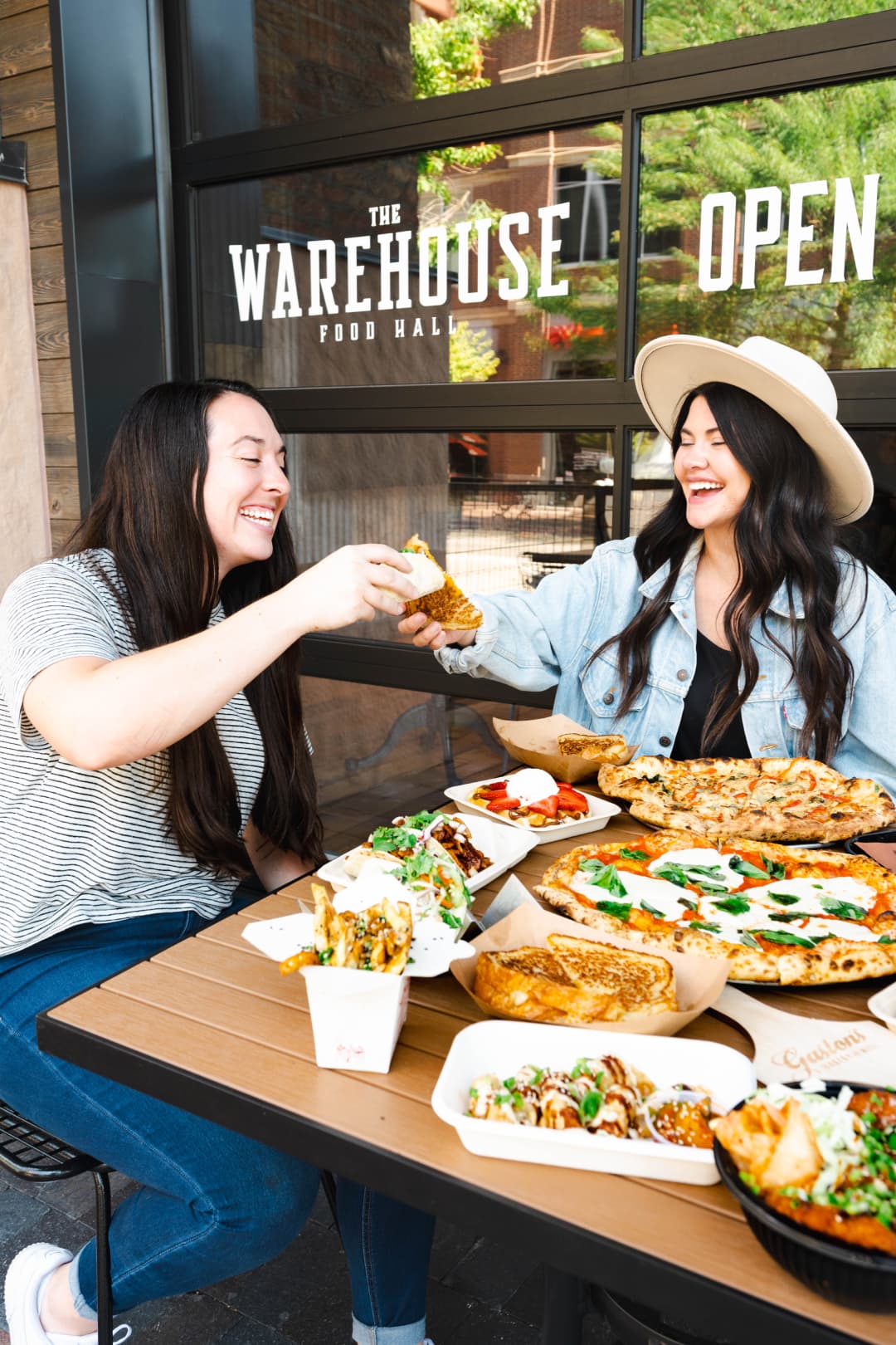 Two people enjoying food in front of the Warehouse Food Hall